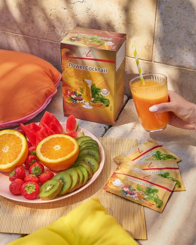 FitLine PowerCocktail Frischer Obstteller mit Kiwi, Erdbeeren, Melone und Orangensaft in sonniger Atmosphäre.