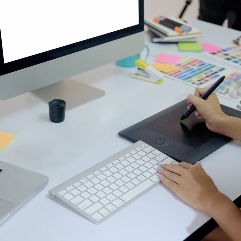 Graphikdesign Ein Schreibtisch mit einem Computer, Grafiktablett und bunten Notizen.