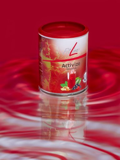 Activize Oxyplus Dose mit rotem Deckel, auf reflektierender Oberfläche, vor rotem Hintergrund.